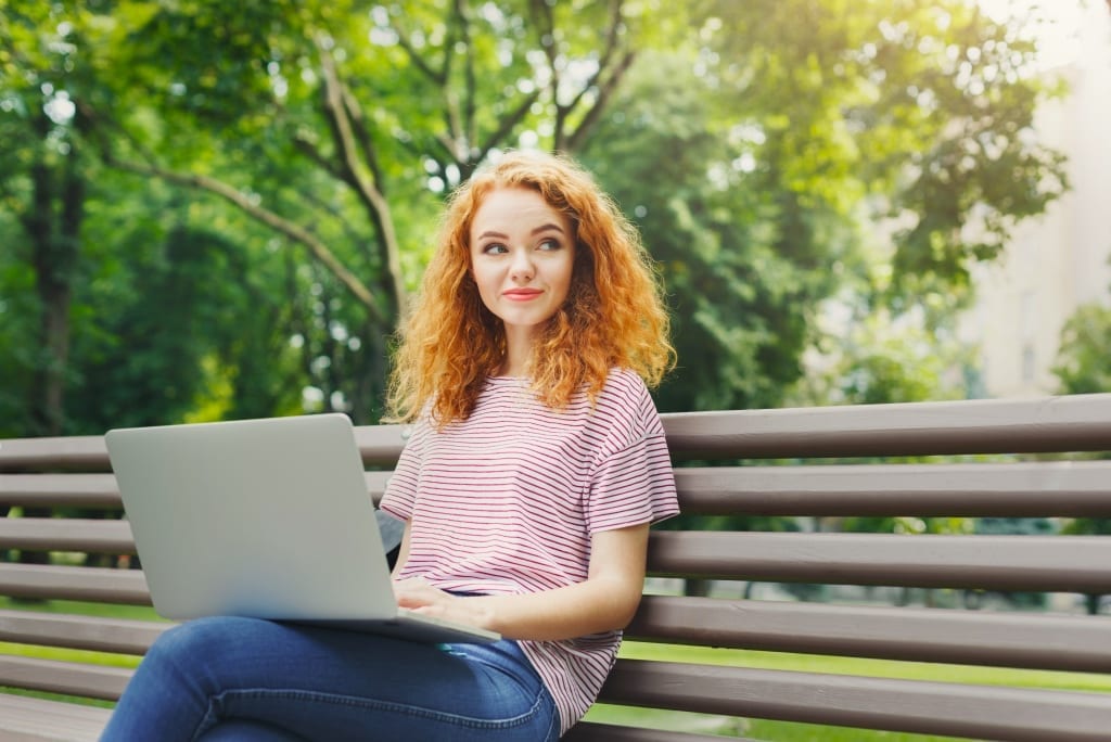 Happy businesswoman freelancer working outside in the park, on her laptop