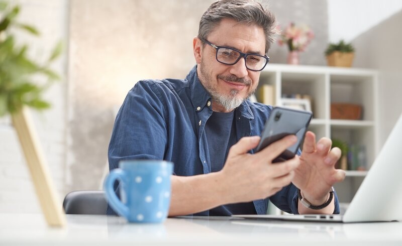 Pleased older male manager looking at phone screen